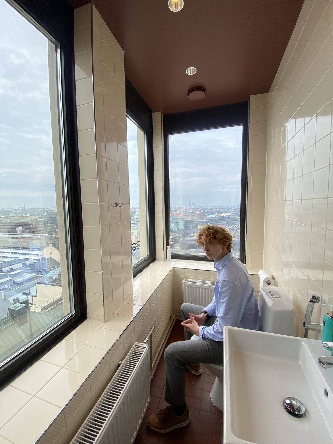 Felix Tinnerholm looking out over Helsinki from a high bathroom window at Hotel Torni