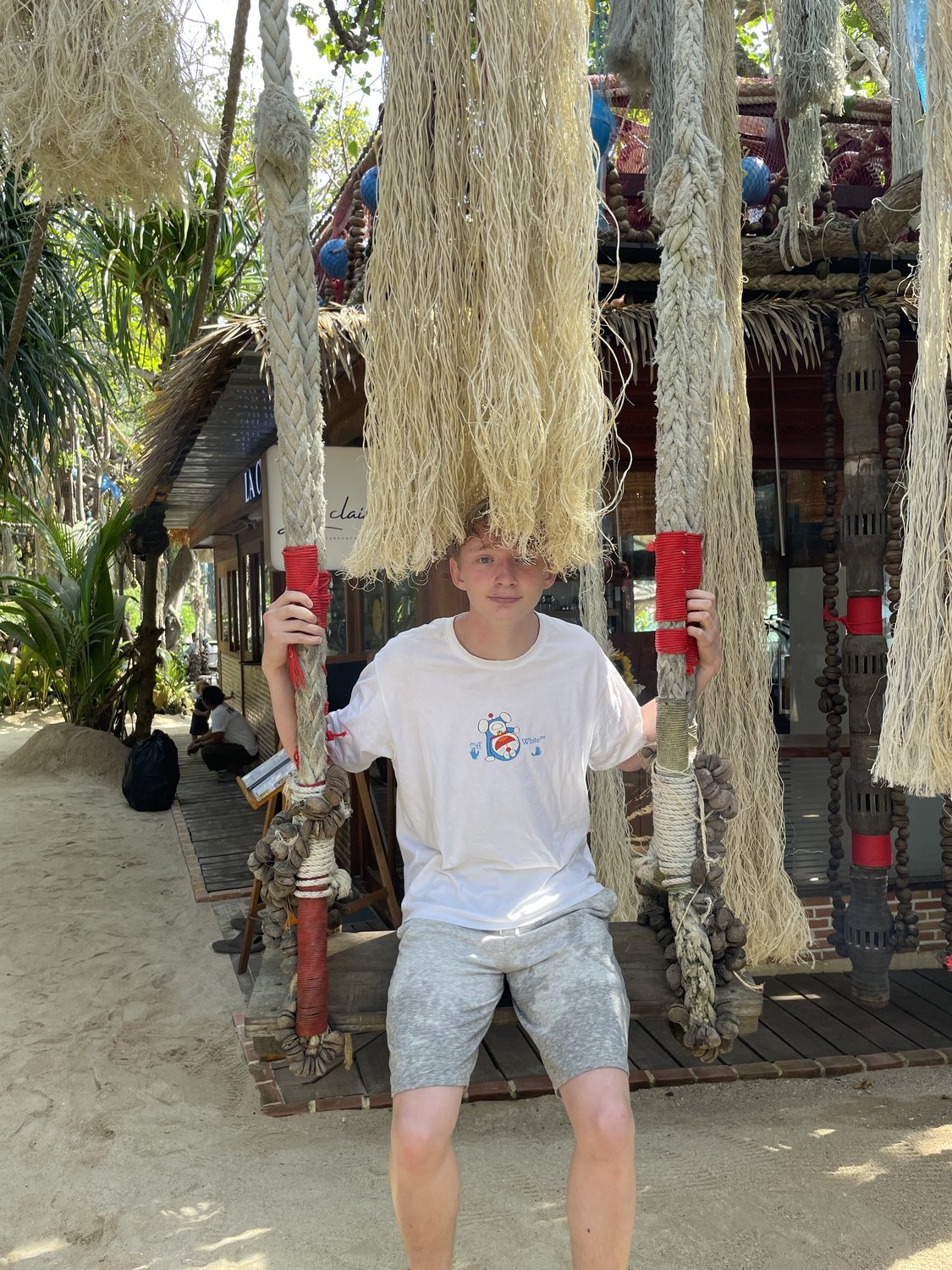 Felix Tinnerholm on a rope swing at a beach restaurant hung with fishing nets